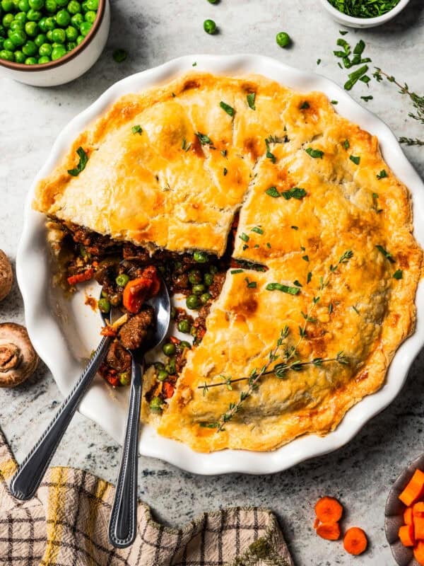 Beef pot pie served in a pie plate with a slice removed from it to expose the meat filling.