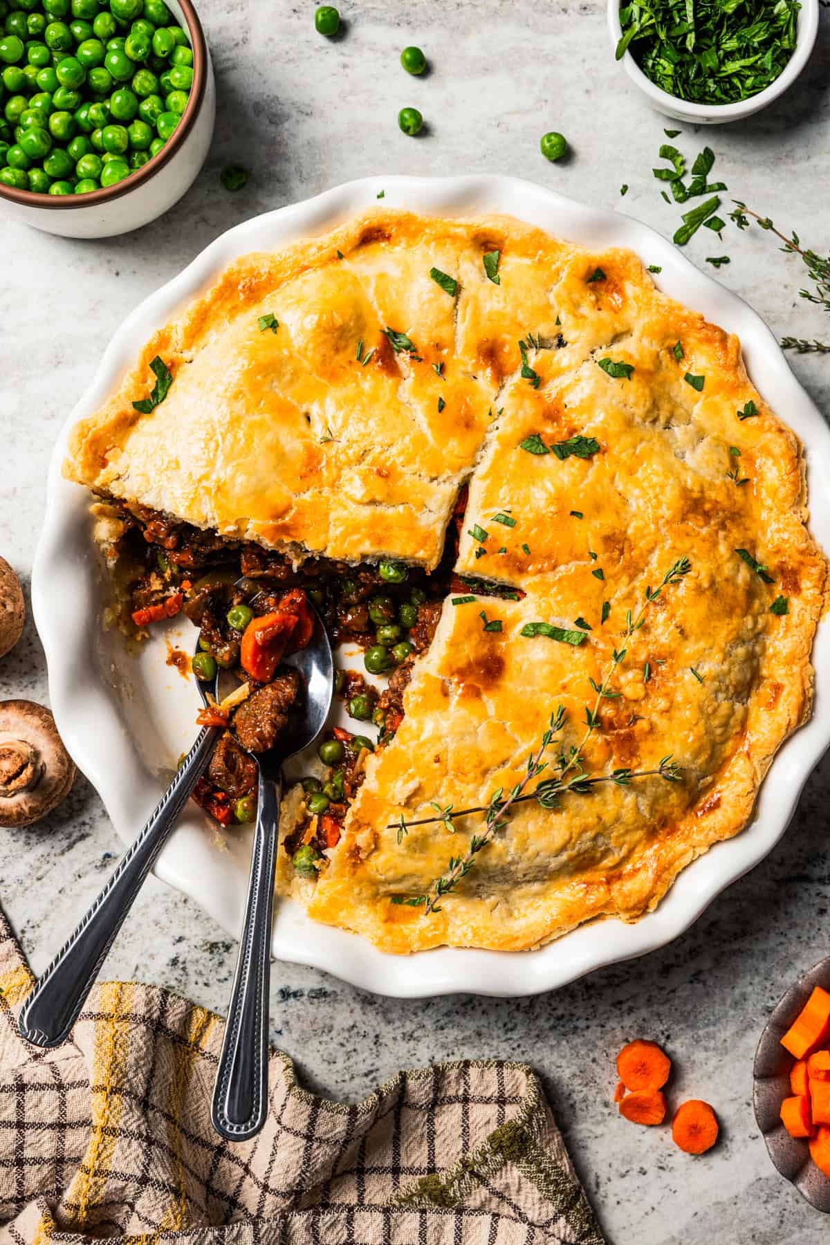 This easy beef pot pie recipe has a hearty, savory filling of juicy braised beef and tender veggies baked inside a flaky homemade pie crust. Beef pot pie served in a pie plate with a slice removed from it to expose the meat filling.