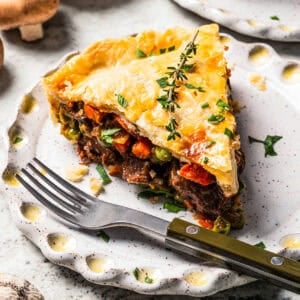 A slice of beef pot pie served on a plate with a fork.