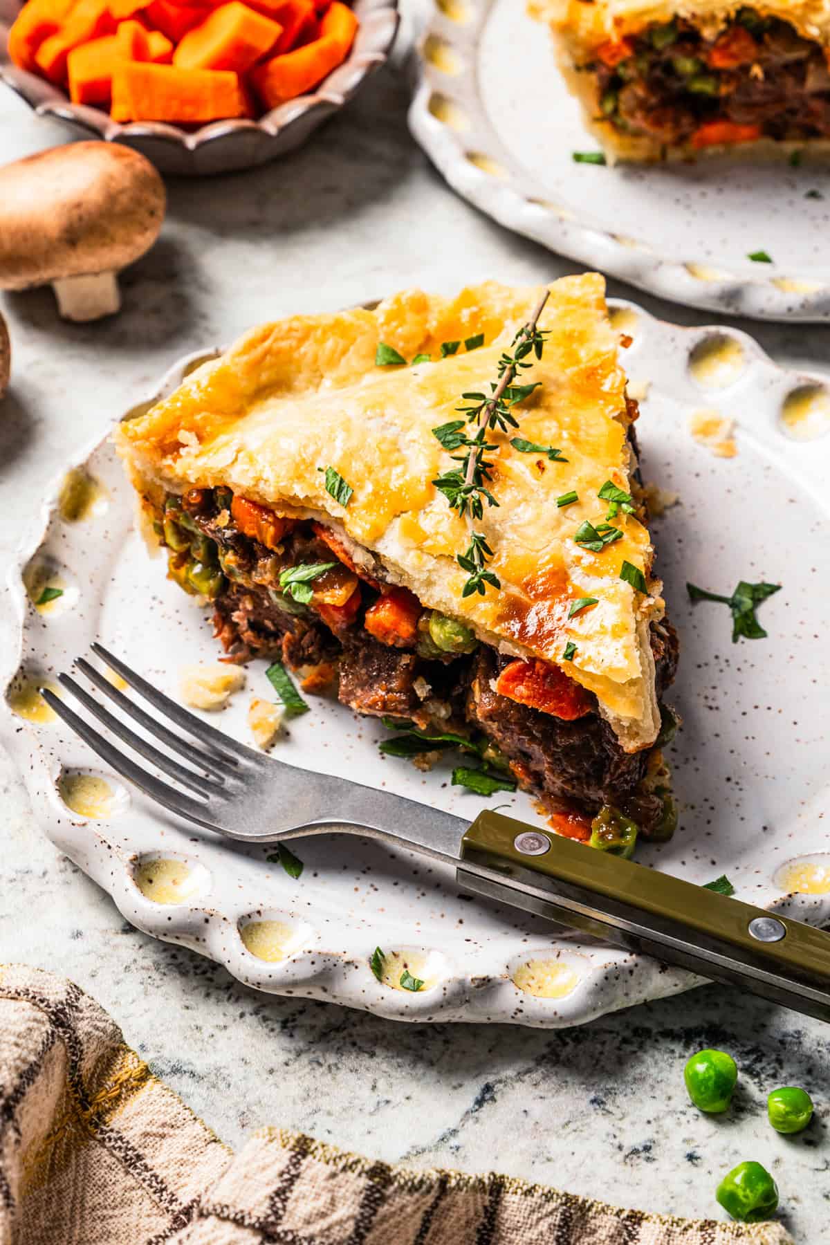 This easy beef pot pie recipe has a hearty, savory filling of juicy braised beef and tender veggies baked inside a flaky homemade pie crust. A slice of beef pot pie served on a plate with a fork.