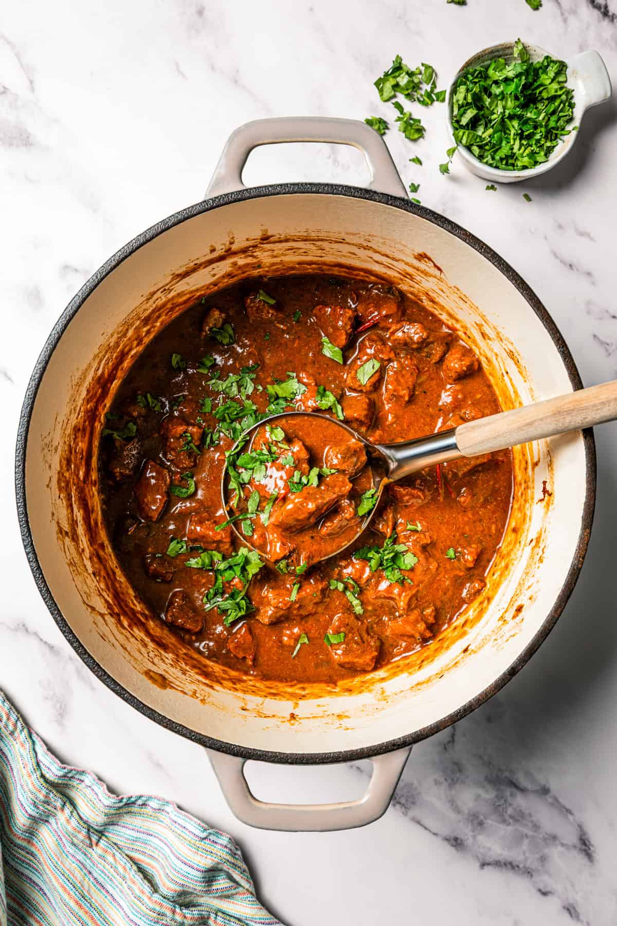 Carne guisada is a flavorful Latin stew with juicy beef slow-cooked in gravy with tomatoes, jalapeños, and spices. Make it at home in one pot! Carne guisada in a large pot.