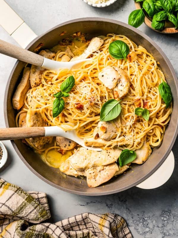 Chicken carbonara in a pot with two serving spoons.