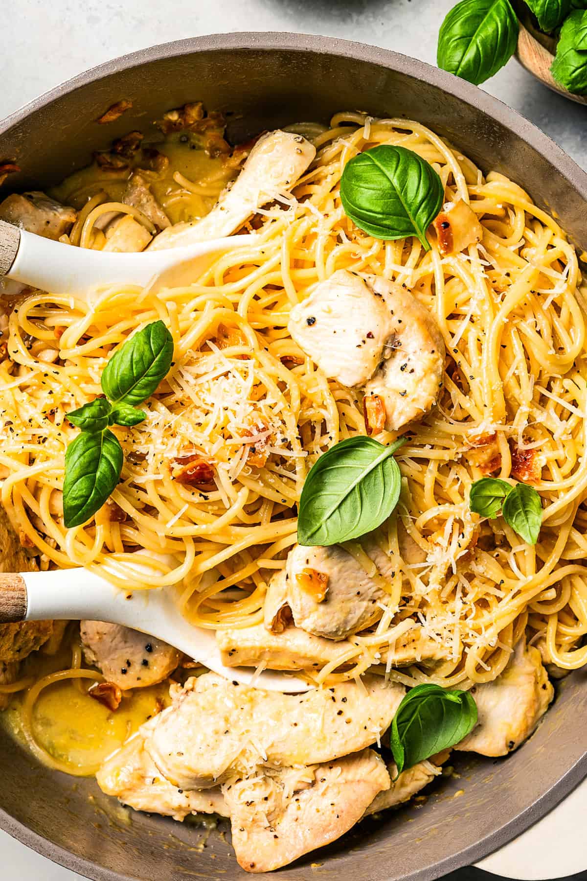 Make the best chicken carbonara in 30 minutes! This is a creamy pasta with parmesan, pancetta, and tender chicken, perfect for weeknights. Overhead view of chicken carbonara in a pot with two serving tongs.