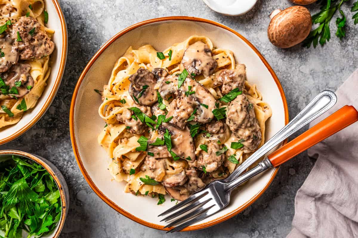 This easy hamburger stroganoff recipe is quick to make in one skillet! Creamy, cozy, and budget-friendly, it's a favorite ground beef dinner. Creamy hamburger stroganoff served with egg noodles in a bowl.