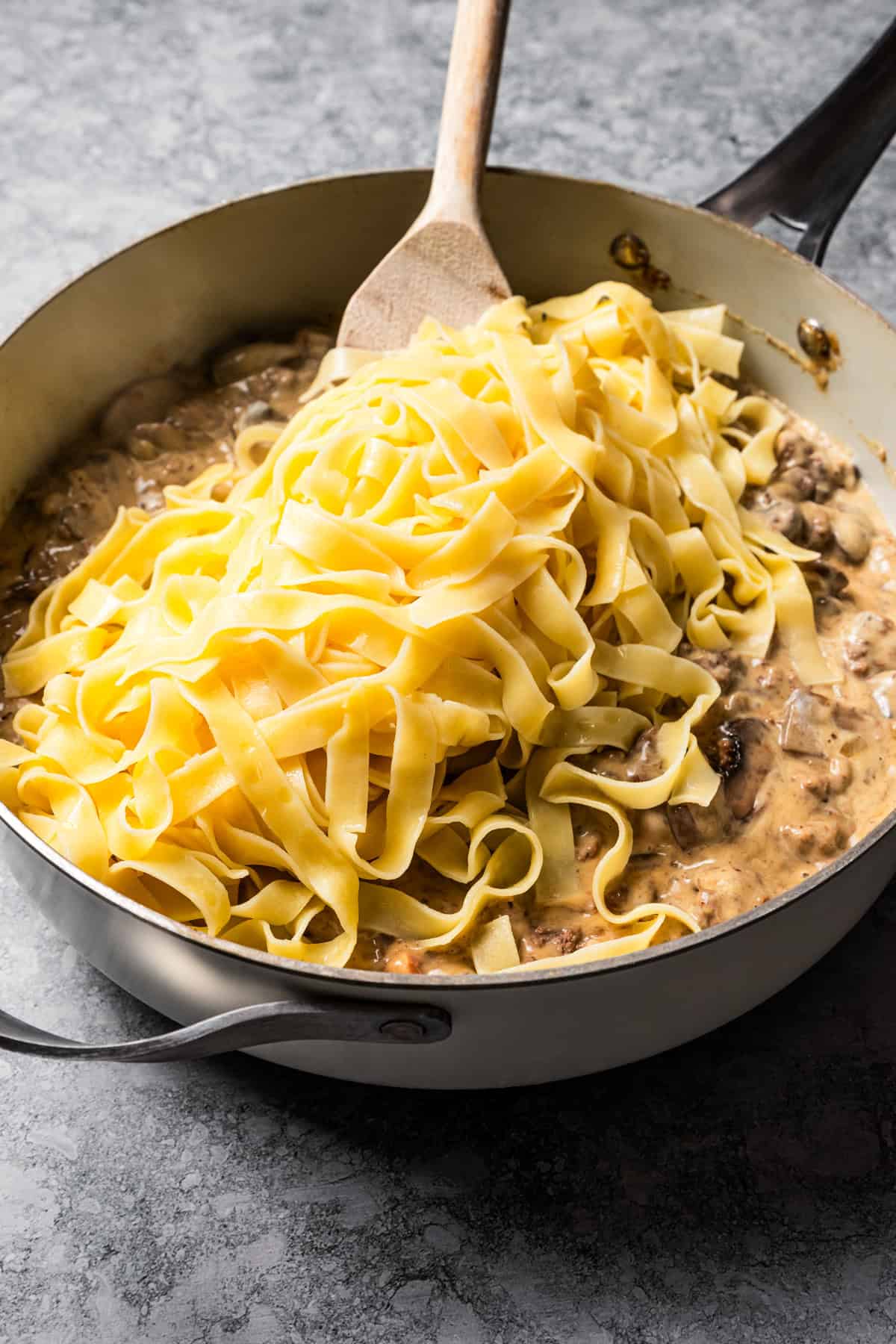 Tossing noodles in a skillet with sauce.