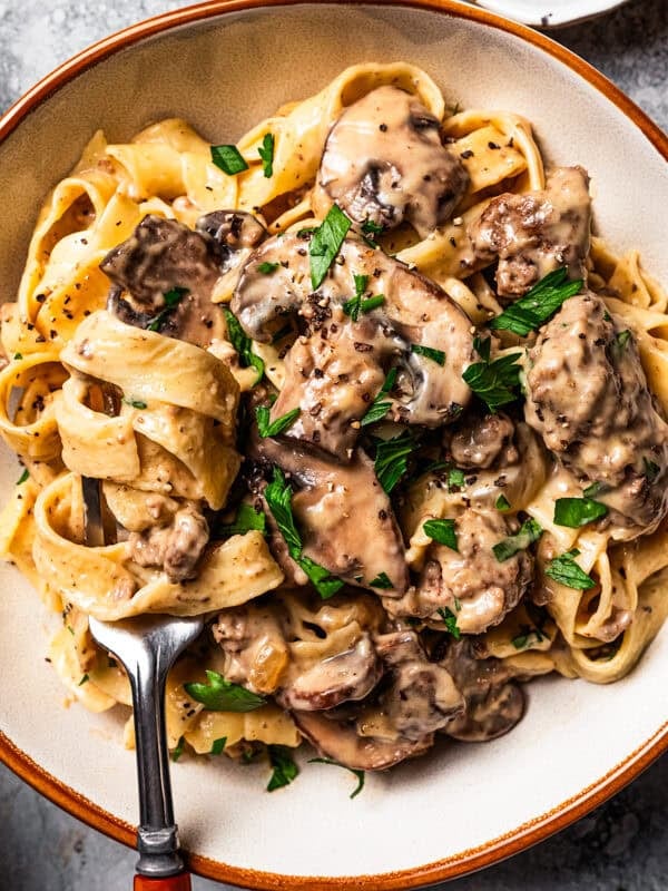 Hamburger stroganoff served over egg noodles in a bowl.