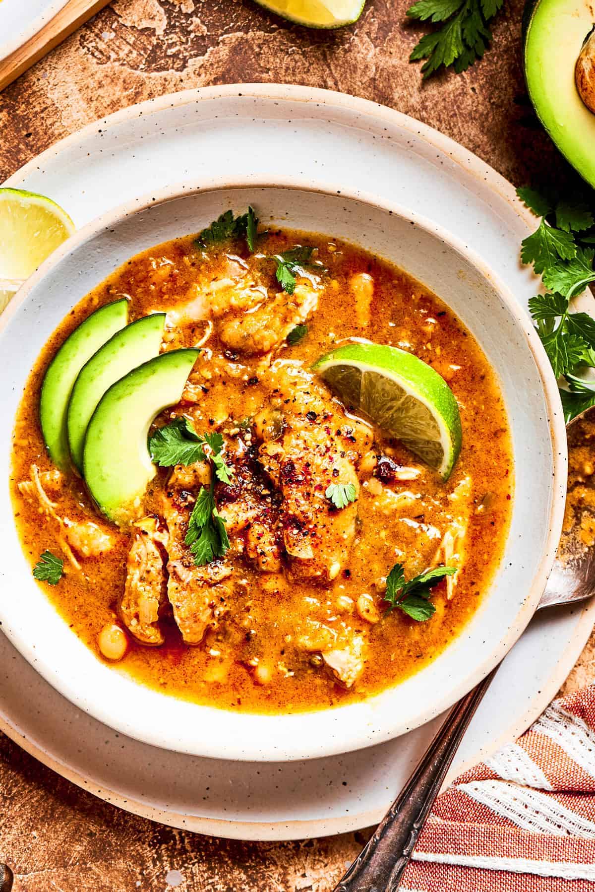 Weekly Menu Plan A bowl of spicy chicken soup garnished with a lime wedge and avocado slices.