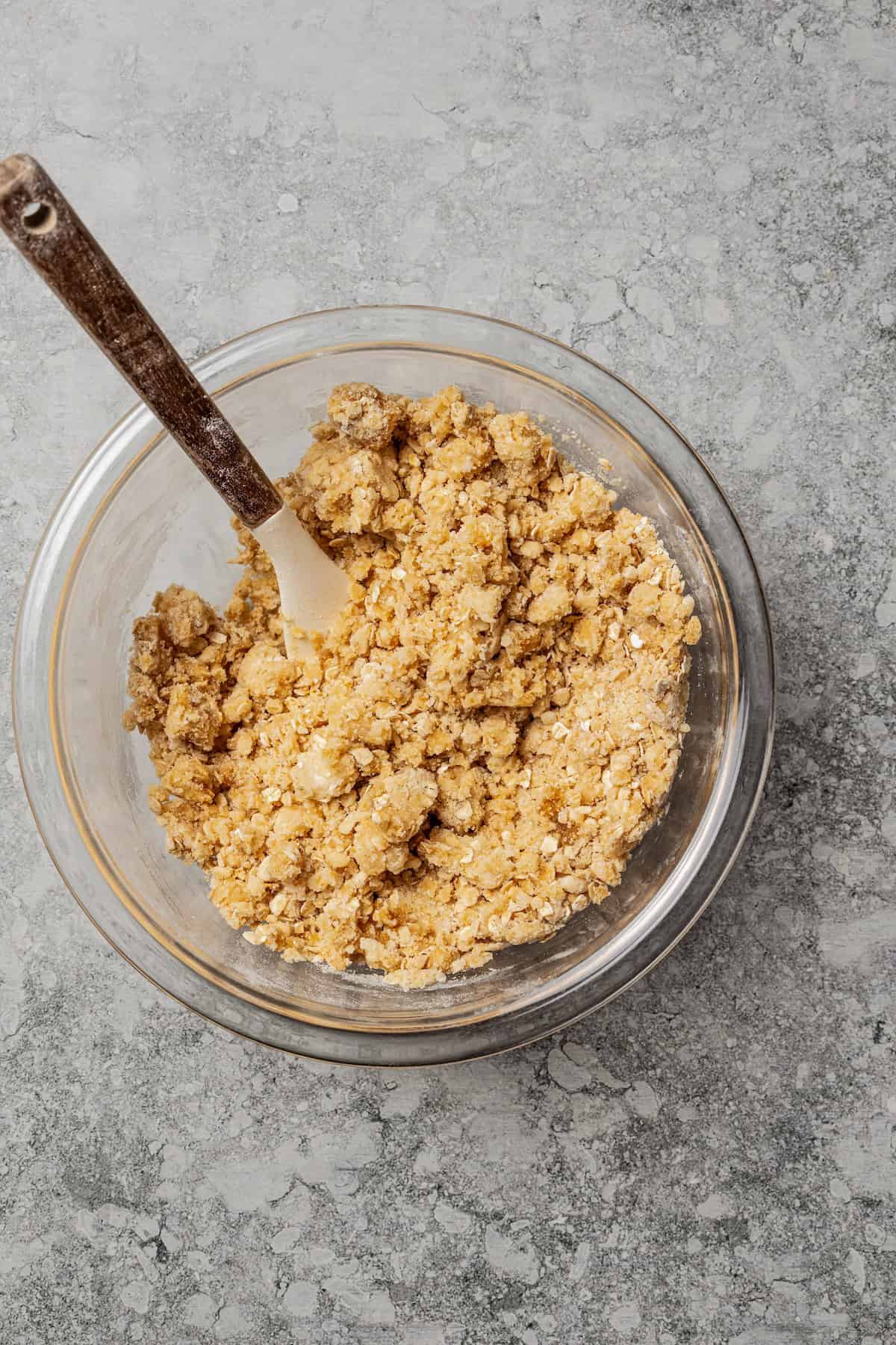 This old-fashioned apple crisp is a classic dessert, with apples, real apple cider, and warm spices baked under a light, crispy oat topping. Crumble topping in a glass bowl.