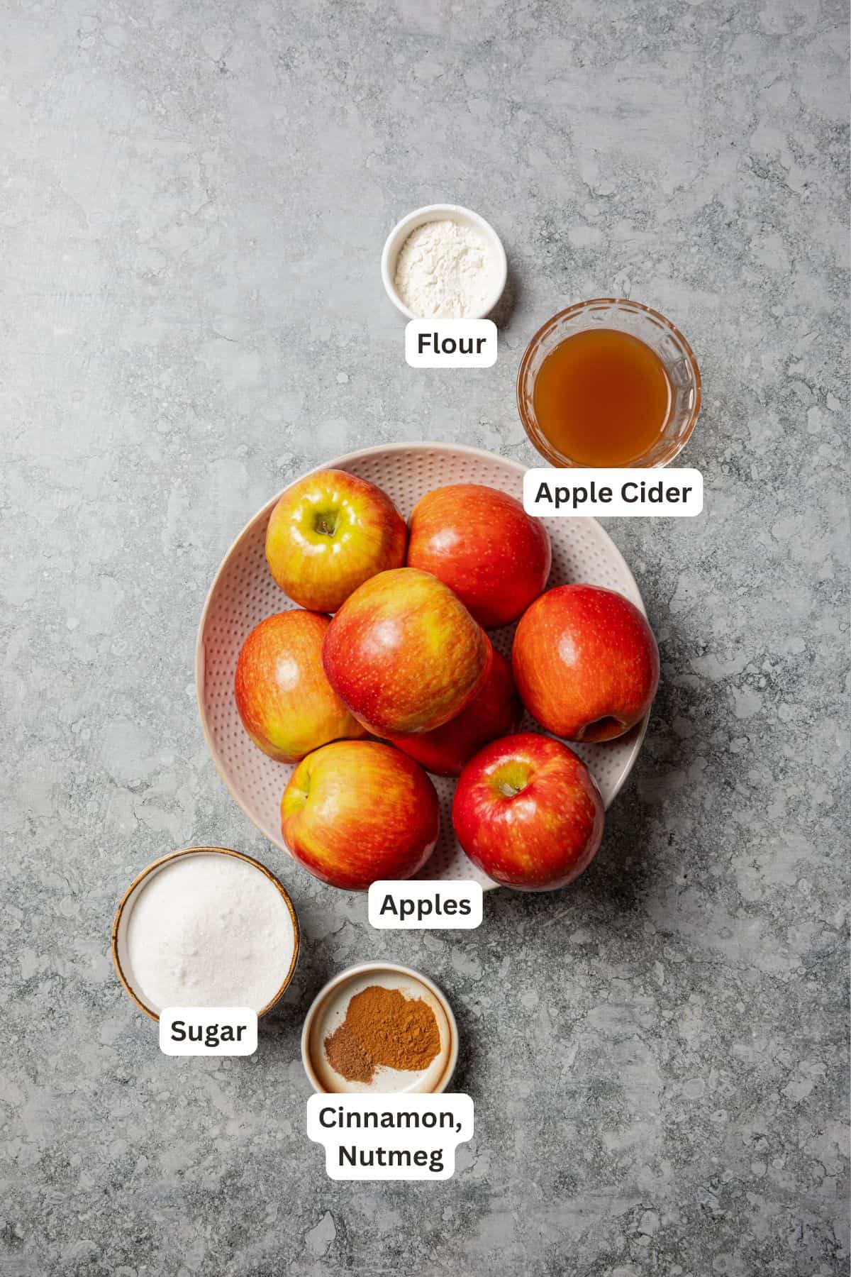 This old-fashioned apple crisp is a classic dessert, with apples, real apple cider, and warm spices baked under a light, crispy oat topping. Apple crisp filling ingredients with text labels overlaying each ingredient.