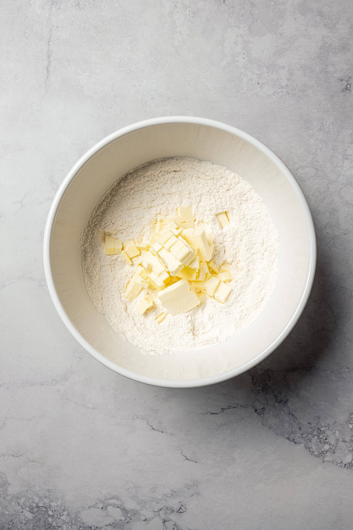 Cold butter added to a bowl of dry ingredients.