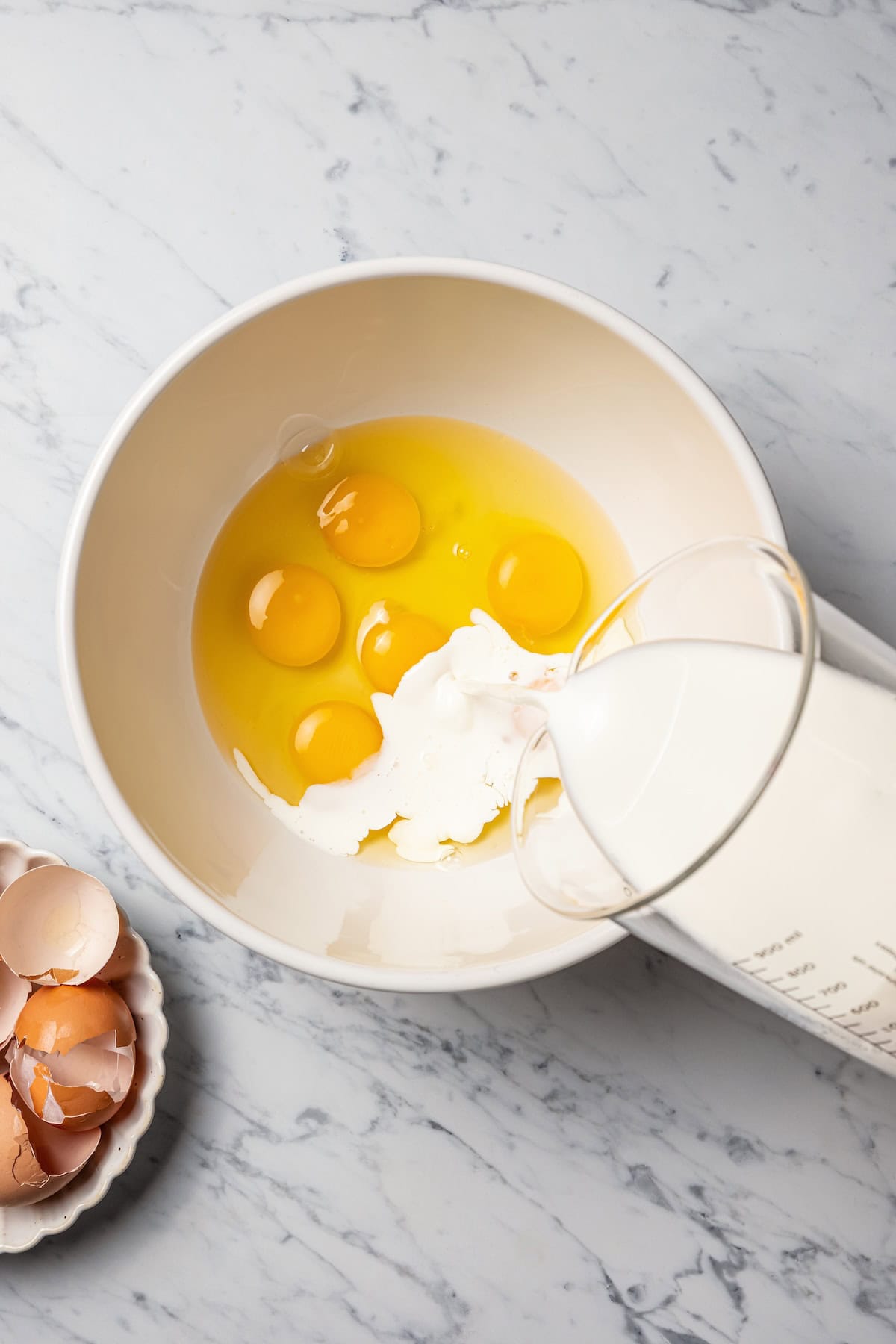 Make thick, fluffy challah bread French toast soaked in an eggy custard with cinnamon, vanilla, and grated nutmeg. The best weekend breakfast! Milk being added to eggs in a mixing bowl to make the custard.