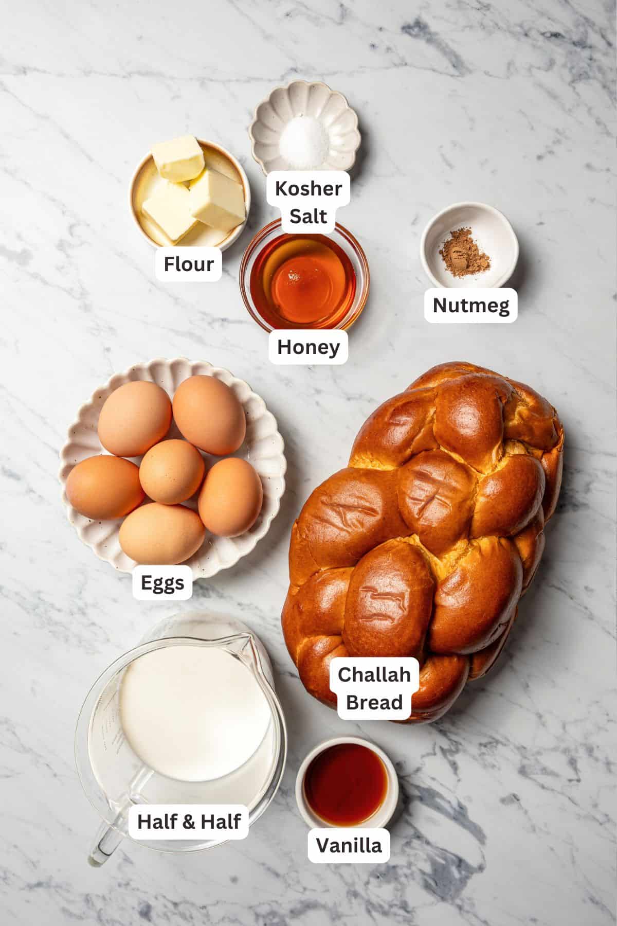 Make thick, fluffy challah bread French toast soaked in an eggy custard with cinnamon, vanilla, and grated nutmeg. The best weekend breakfast! Challah French toast ingredients with text labels overlaying each ingredient.