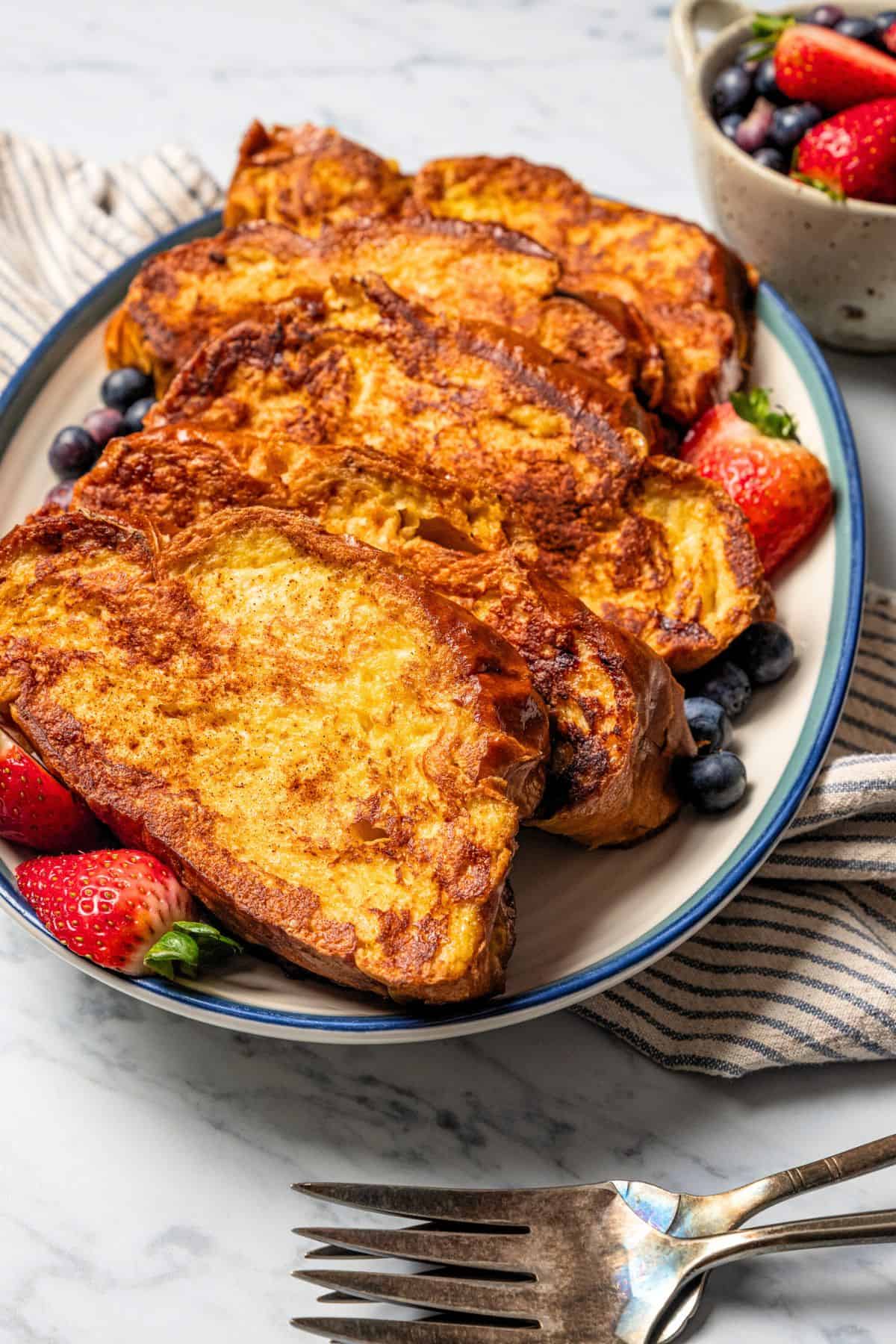 Make thick, fluffy challah bread French toast soaked in an eggy custard with cinnamon, vanilla, and grated nutmeg. The best weekend breakfast! French toast slices served on a platter.