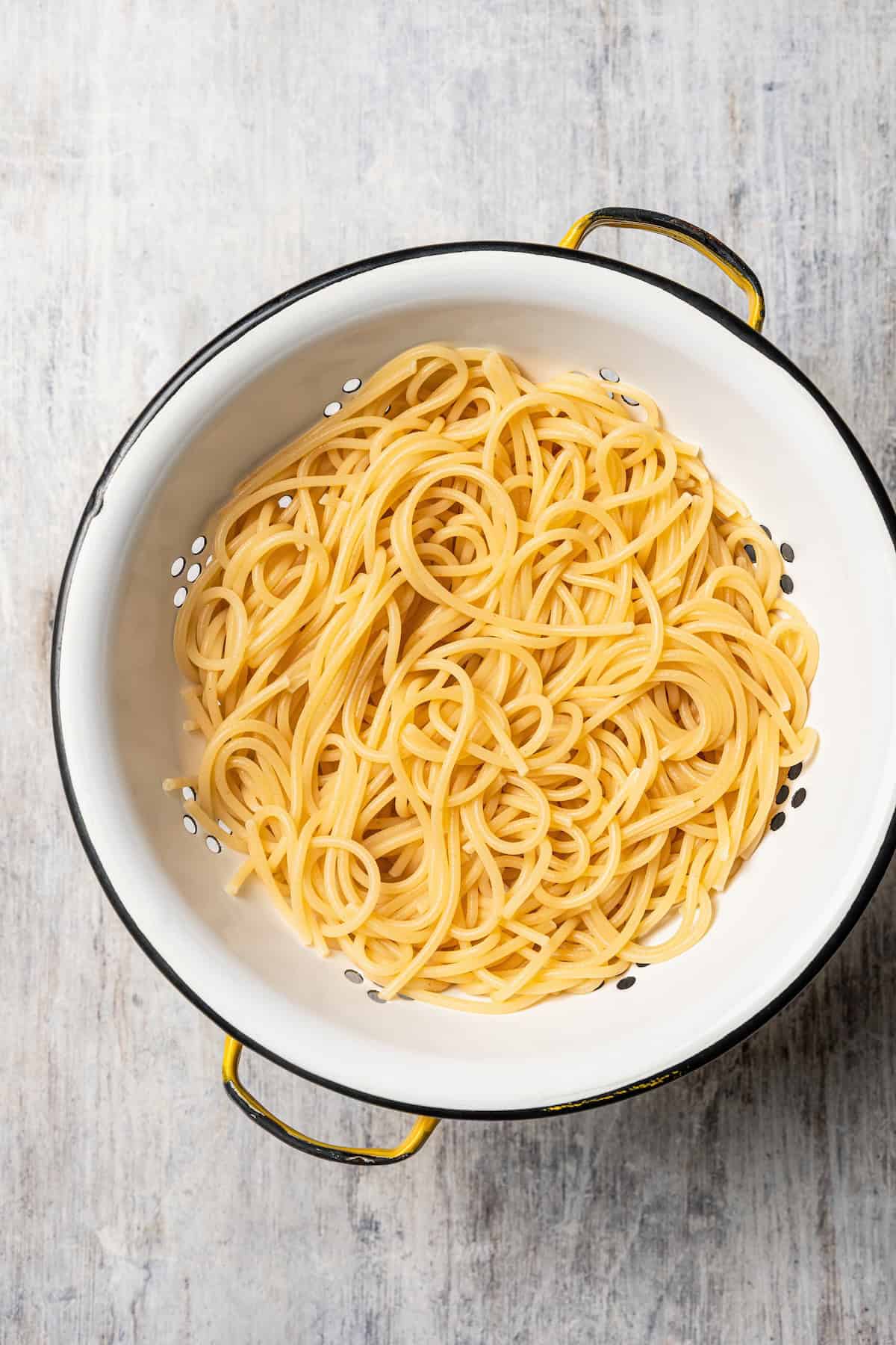 This chicken and bacon pasta is a 20-minute meal with tender linguine, juicy chicken, bacon, and parmesan in a creamy, Carbonara-style sauce. Drained pasta in a colander.