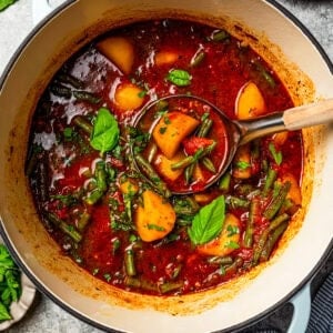 Braised potatoes in a pot, with a ladle scooping out a serving.