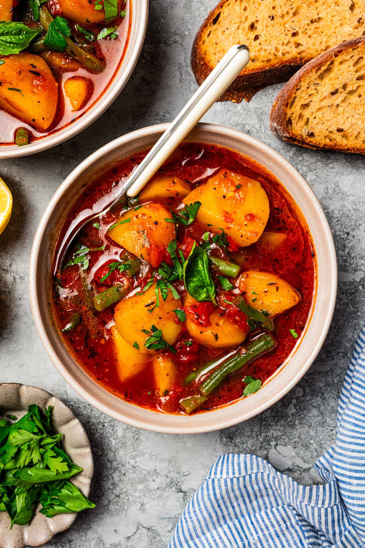 Braised potatoes are slow-cooked with tender green beans and tomatoes in this easy, one-pot Macedonian dish that warms from the inside out. Macedonian braised potatoes in a bowl with a spoon.