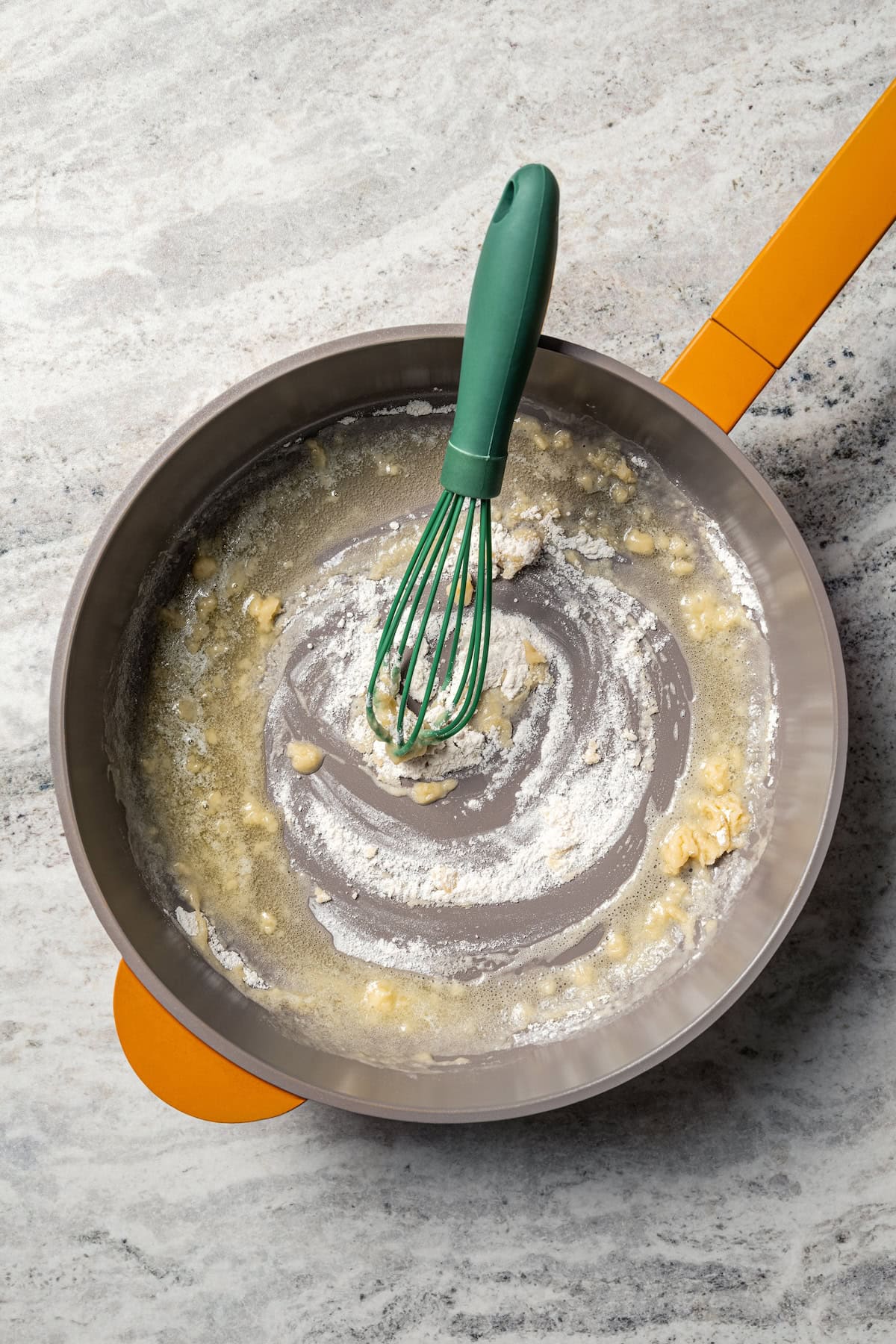 This easy scalloped potatoes recipe has thinly sliced potatoes smothered and baked in a flavorful cream sauce with nutmeg and Gruyère cheese. Flour partially whisked into melted butter to make a roux in a skillet.