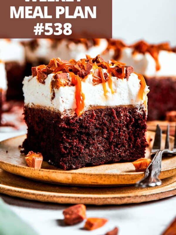 A square cut slice of chocolate cake topped with cream and a drizzle of caramel.