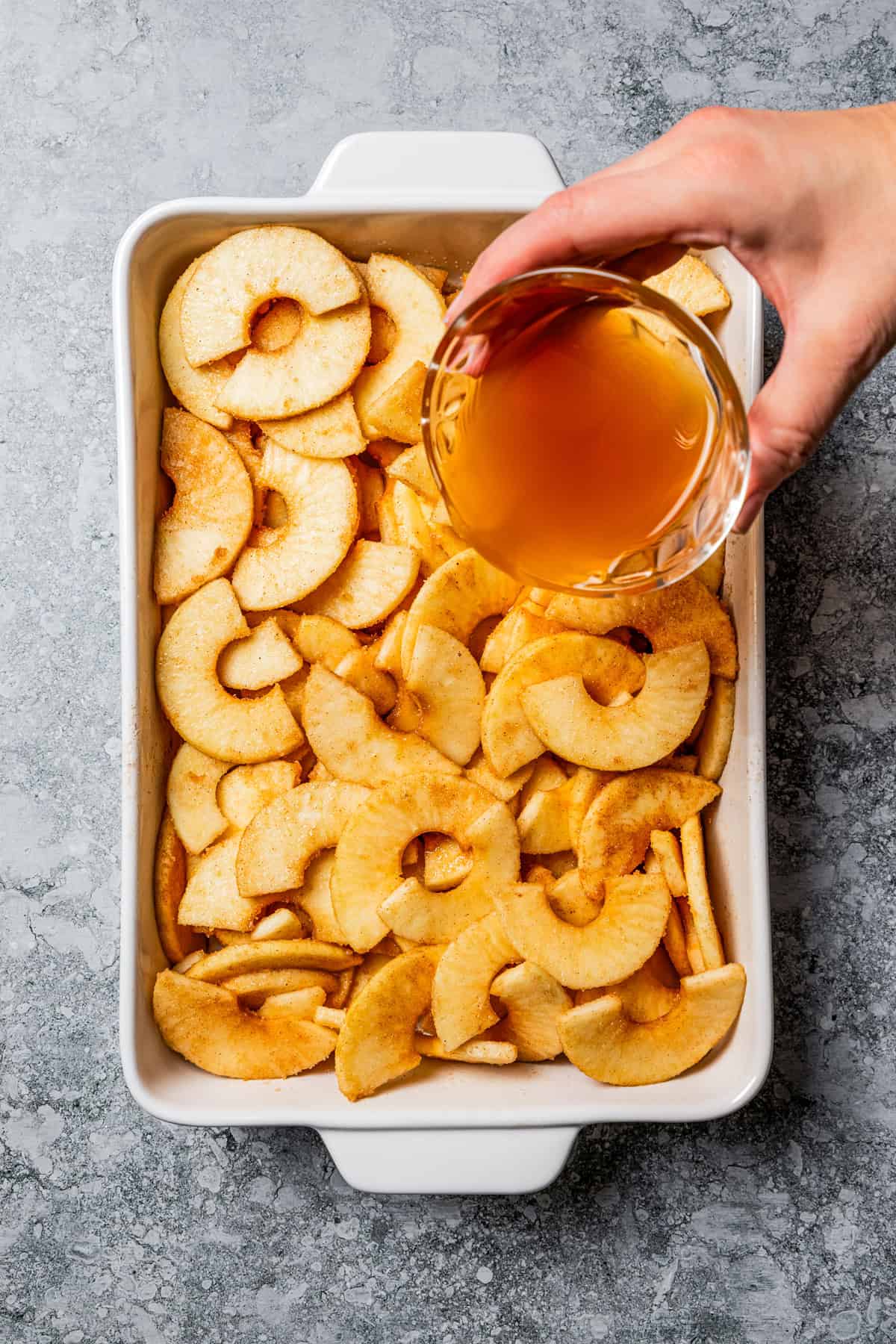 This old-fashioned apple crisp is a classic dessert, with apples, real apple cider, and warm spices baked under a light, crispy oat topping. Pouring apple cider over apple slices tossed with cinnamon.