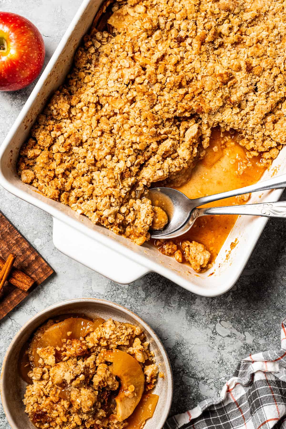 This old-fashioned apple crisp is a classic dessert, with apples, real apple cider, and warm spices baked under a light, crispy oat topping. Apple crisp in a baking dish, with a spoon resting in the corner.