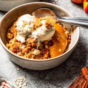 Apple crisp served in bowls and topped with vanilla ice cream.