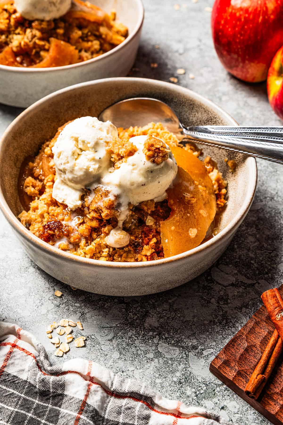 This old-fashioned apple crisp is a classic dessert, with apples, real apple cider, and warm spices baked under a light, crispy oat topping. Apple crisp served in bowls and topped with vanilla ice cream.