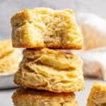 Three buttermilk biscuits stacked up, with a bite missing from the top biscuit.
