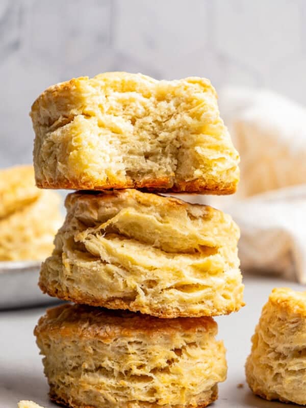 Three buttermilk biscuits stacked up, with a bite missing from the top biscuit.