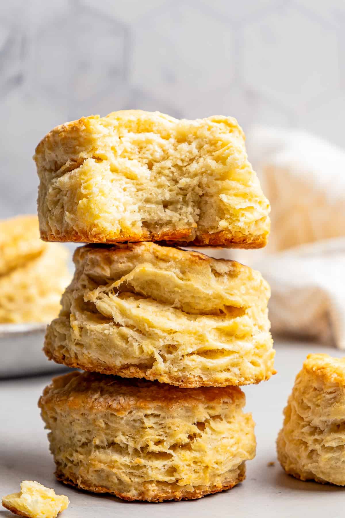 Three buttermilk biscuits stacked up, with a bite missing from the top biscuit.