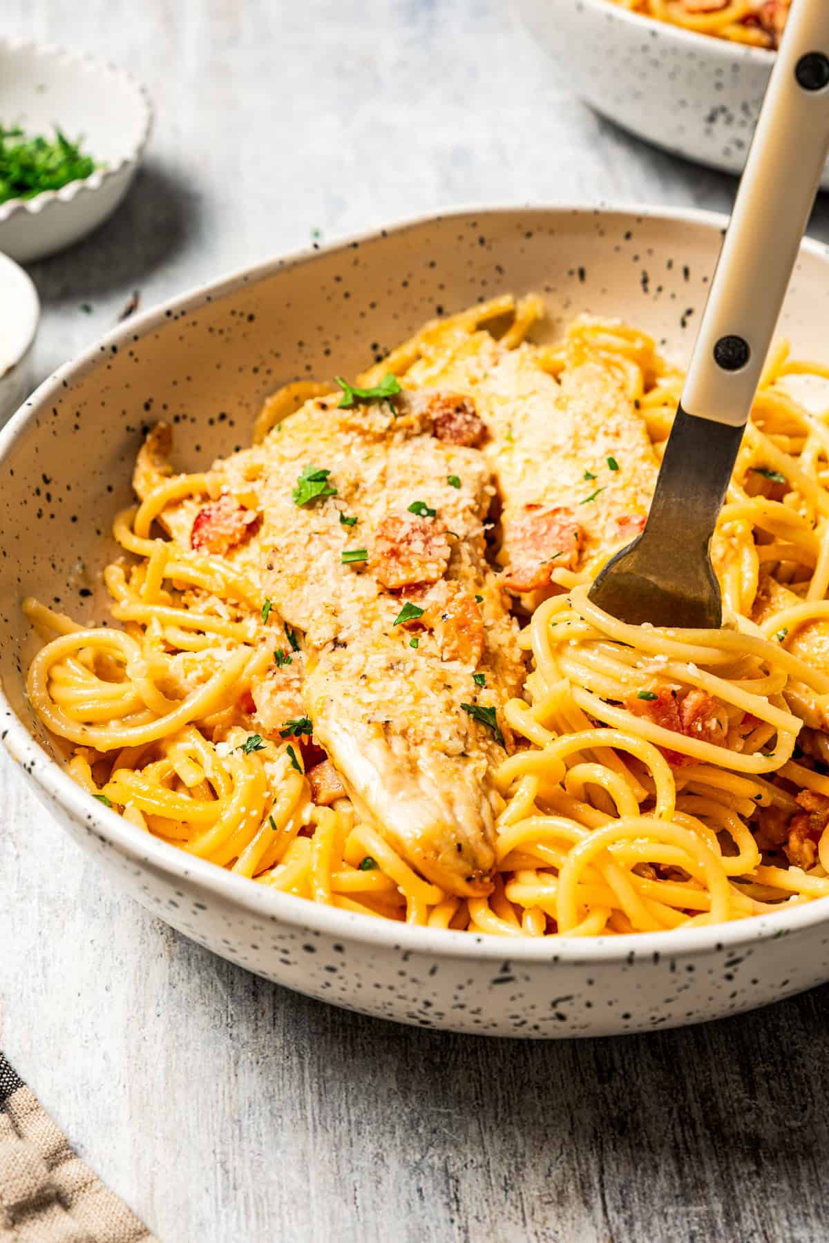 This chicken and bacon pasta is a 20-minute meal with tender linguine, juicy chicken, bacon, and parmesan in a creamy, Carbonara-style sauce. A fork twirling through chicken and bacon pasta.
