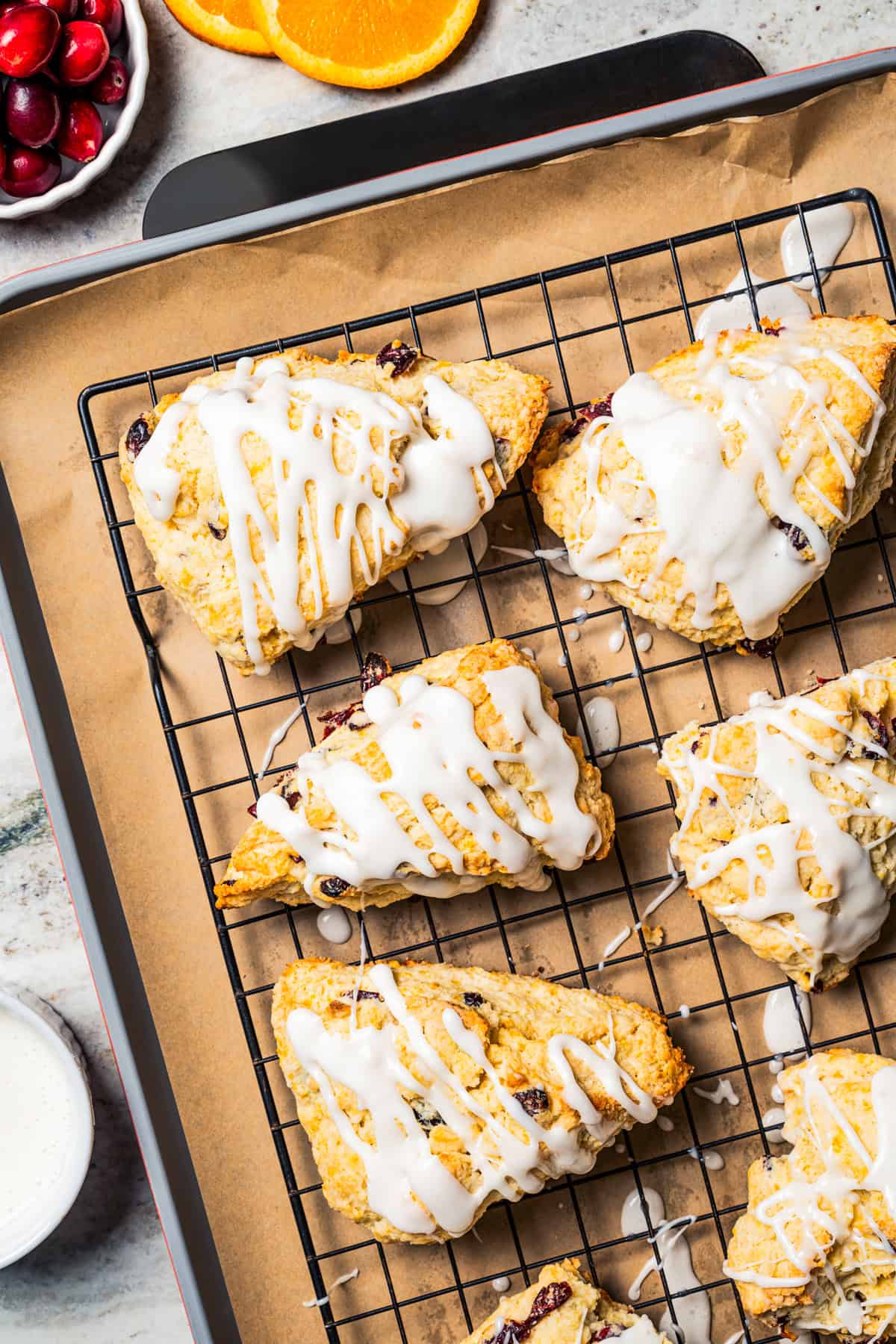 Overhead view of cranberry orange scones drizzled with glaze on a wire rack.