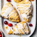 Cranberry orange scones drizzled with glaze and arranged on a serving platter.