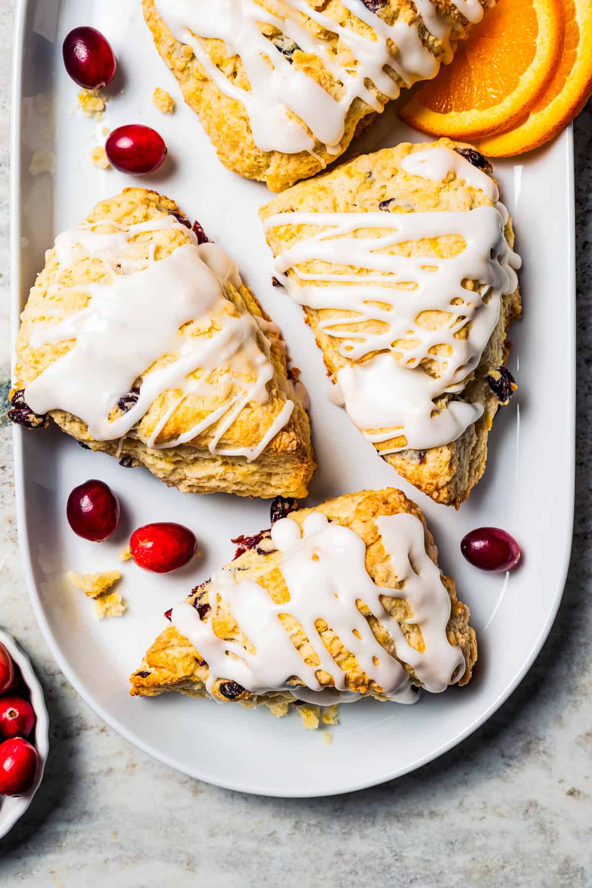 Cranberry orange scones drizzled with glaze and arranged on a serving platter.