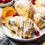 Cranberry orange scones drizzled with glaze on a serving platter.