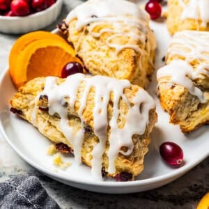 Cranberry orange scones drizzled with glaze on a serving platter.