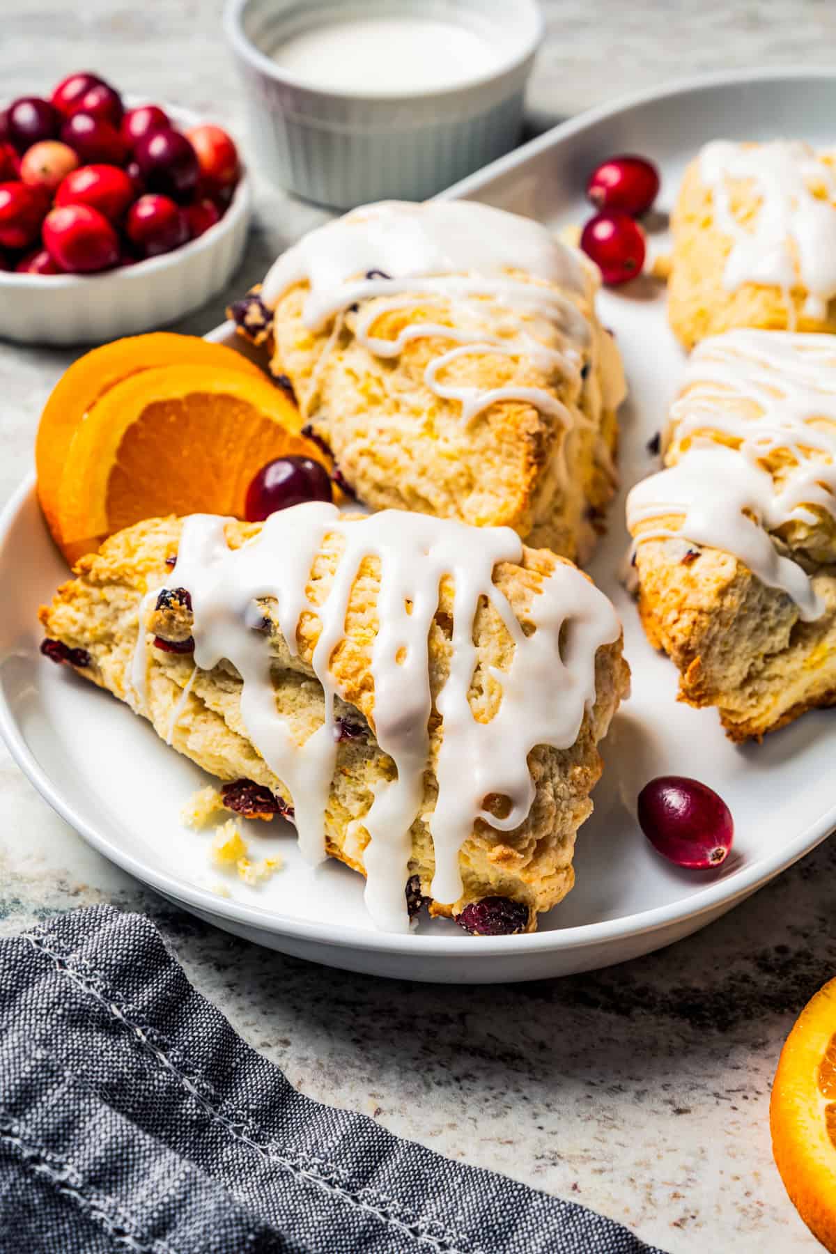 Cranberry orange scones drizzled with glaze on a serving platter.