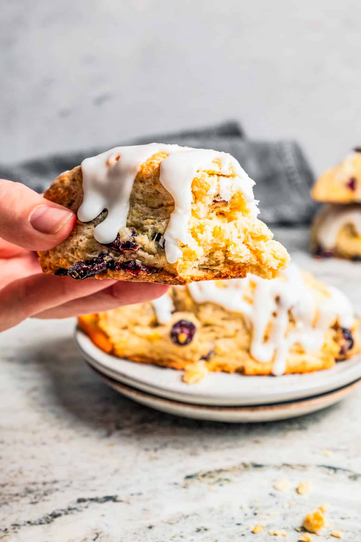 A hand holding up a cranberry scone.