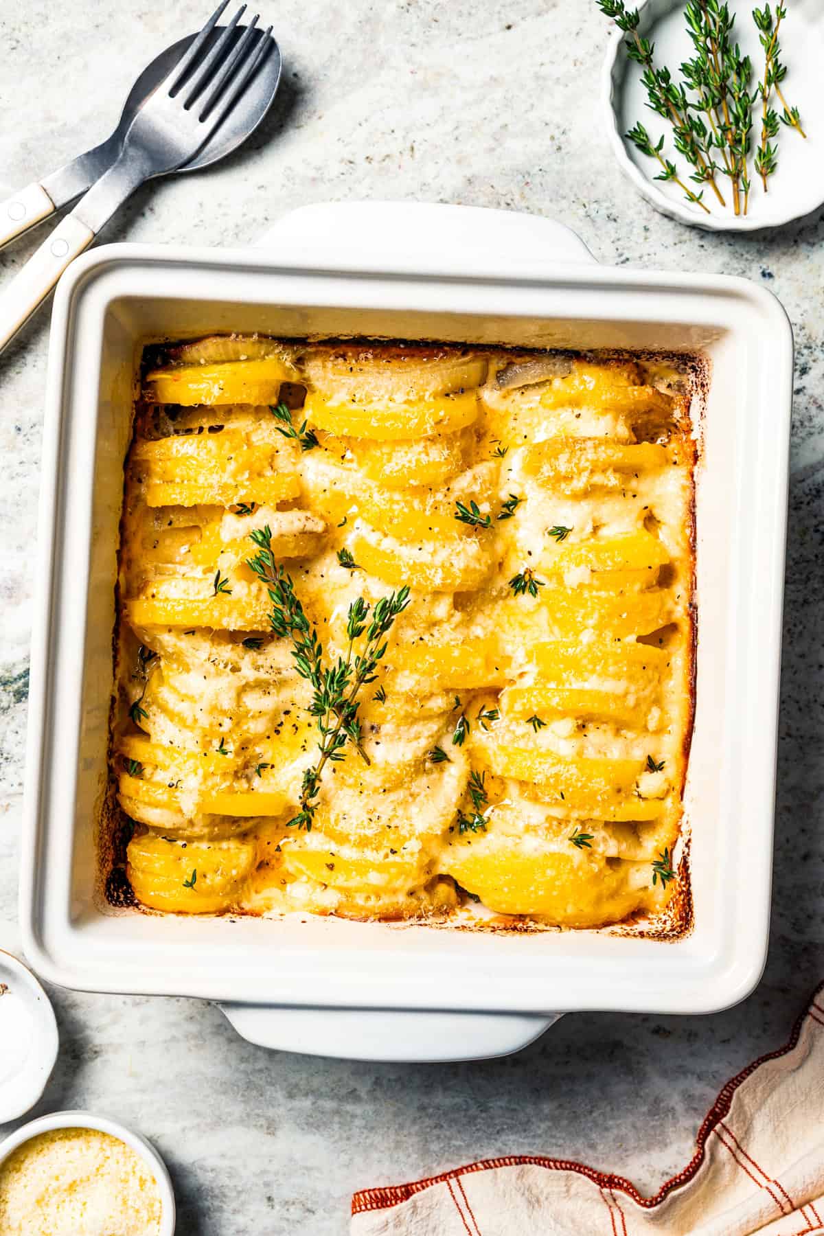 This easy scalloped potatoes recipe has thinly sliced potatoes smothered and baked in a flavorful cream sauce with nutmeg and Gruyère cheese. Baked scalloped potatoes in a baking dish.