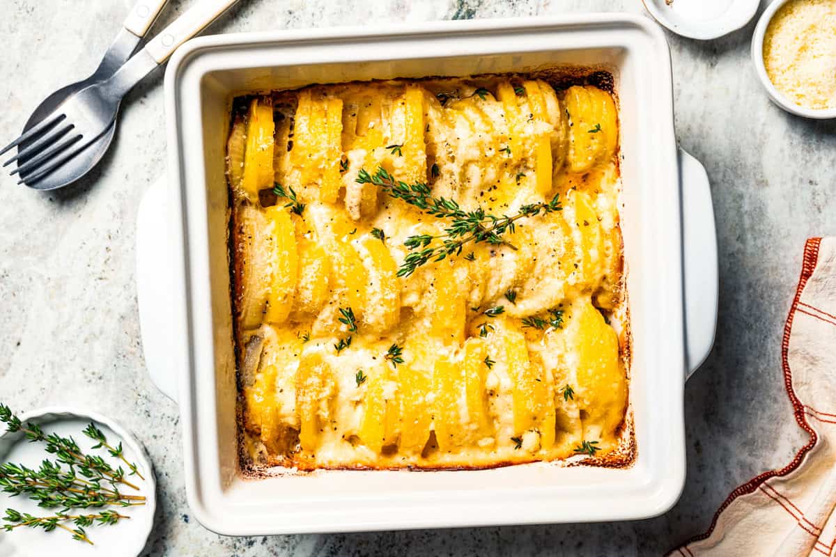 This easy scalloped potatoes recipe has thinly sliced potatoes smothered and baked in a flavorful cream sauce with nutmeg and Gruyère cheese. Baked scalloped potatoes in a baking dish.