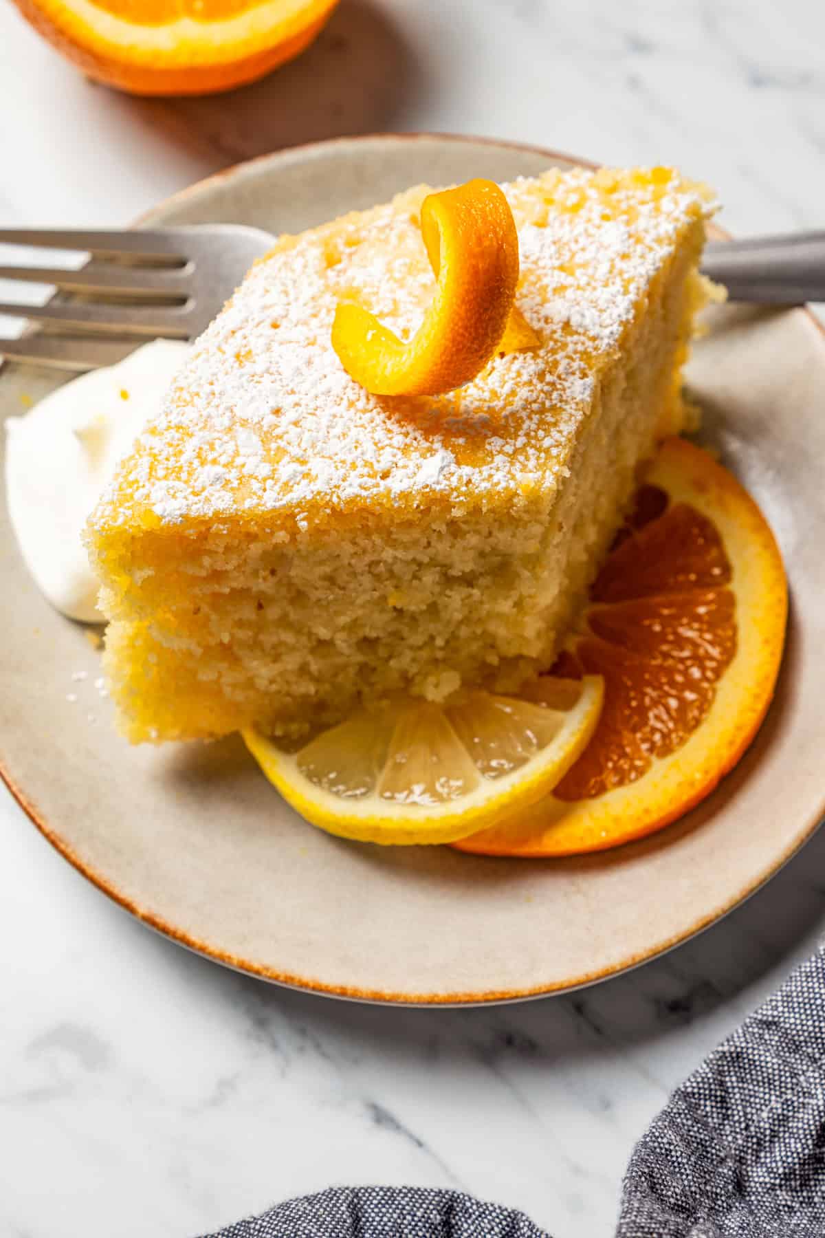 A slice of Ravanija served on a plate with orange slices.