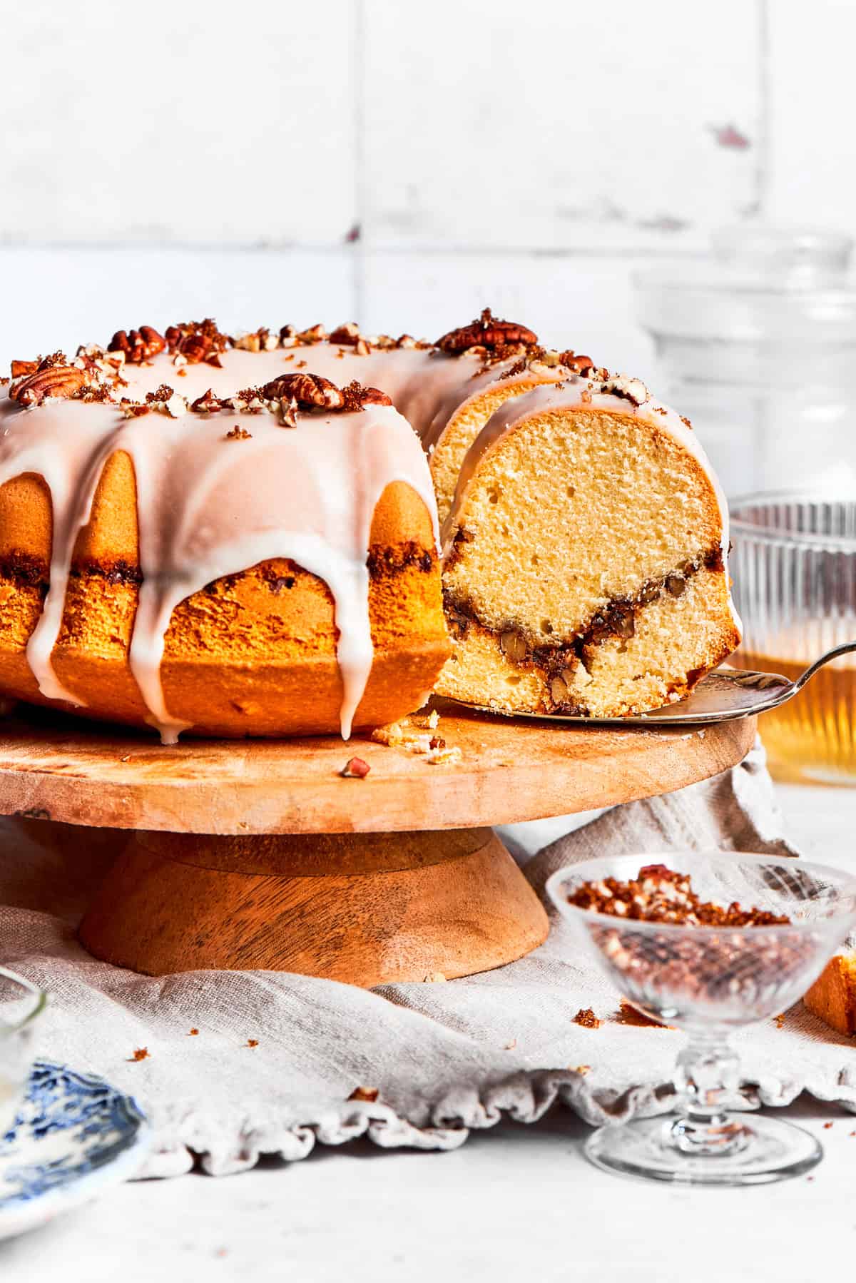 A bundt cake on a cake stand, with a slice being pulled out.