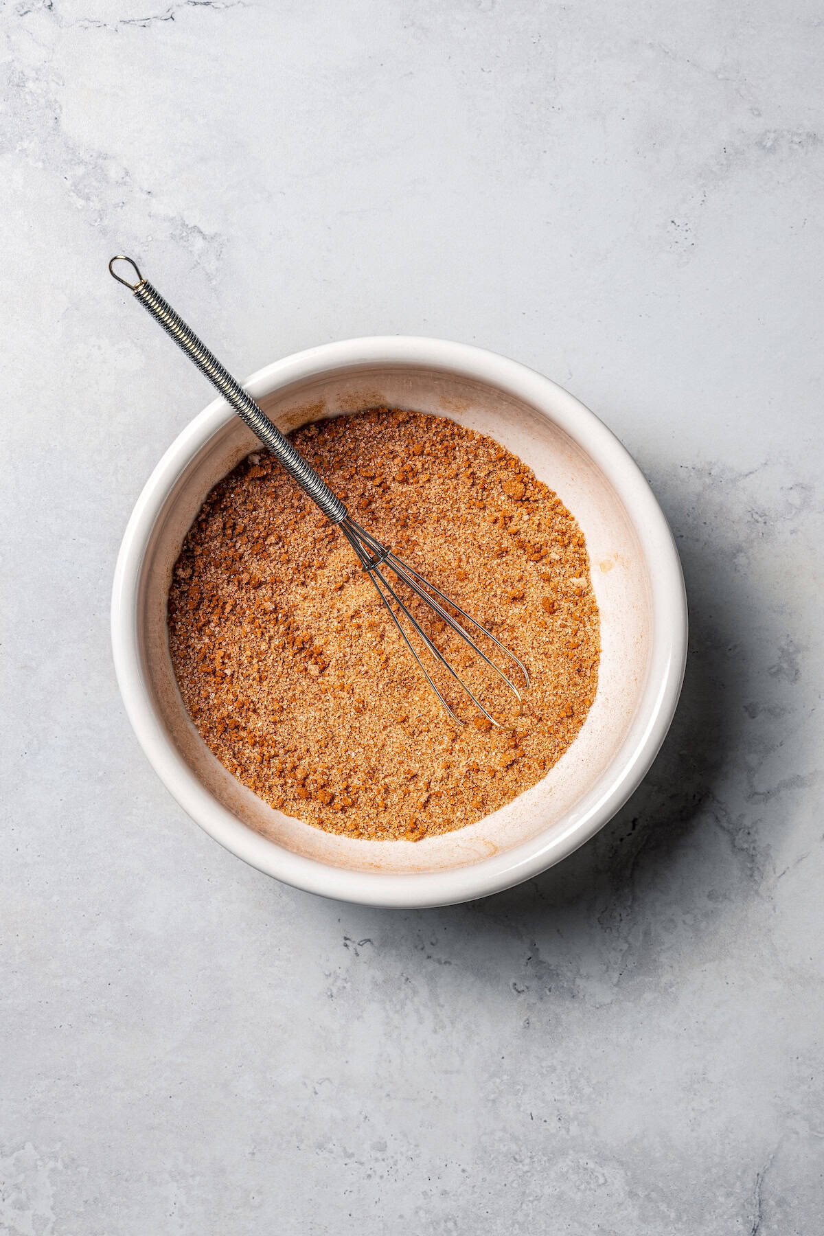 This churro cheesecake bars recipe is an easy dessert with layers of cinnamon sugar, a flaky pastry crust, and creamy cheesecake filling. Cinnamon sugar in a bowl with a whisk.