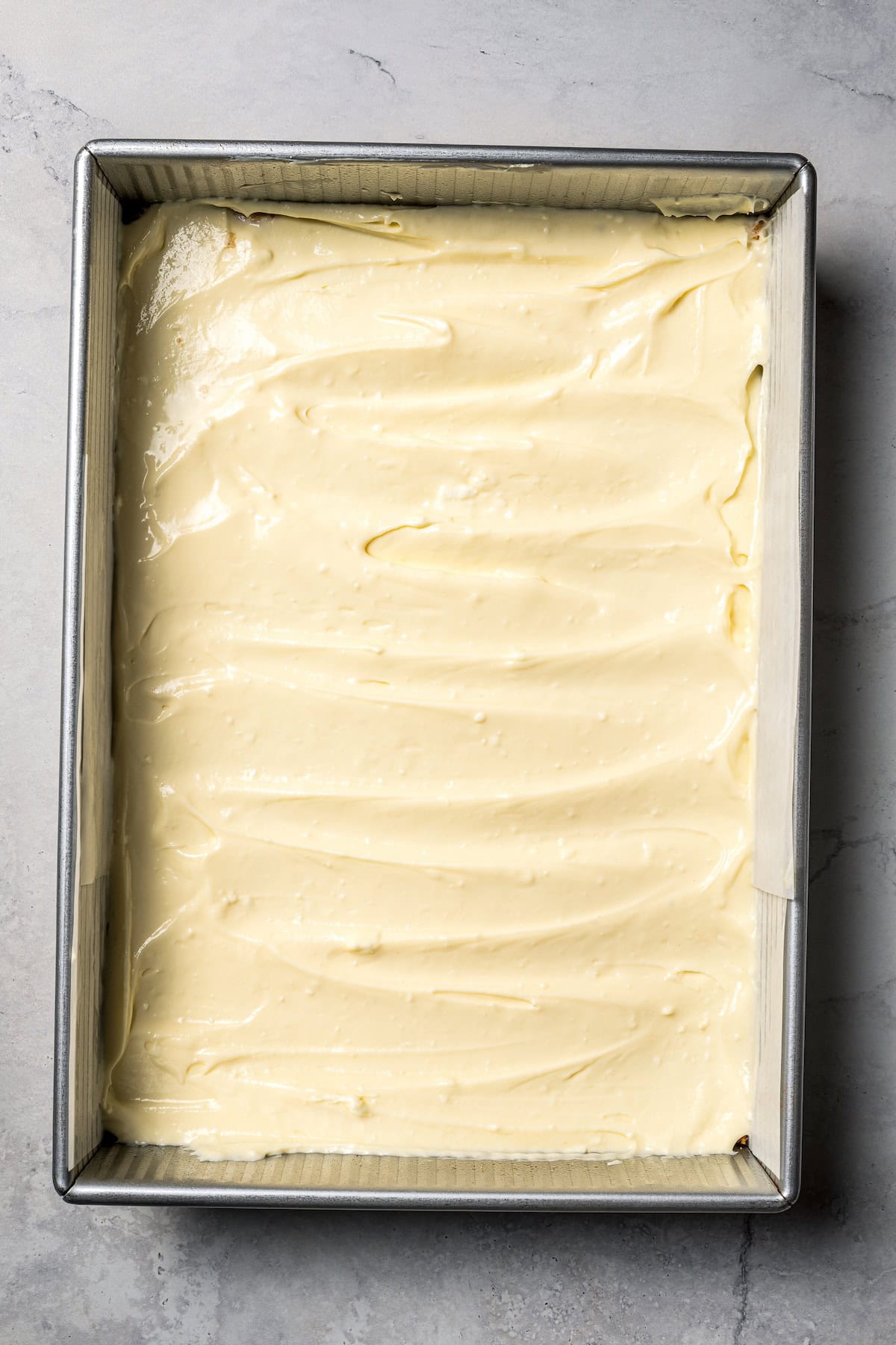 This churro cheesecake bars recipe is an easy dessert with layers of cinnamon sugar, a flaky pastry crust, and creamy cheesecake filling. Cheesecake filling spread on top of the bottom crust in a baking pan.