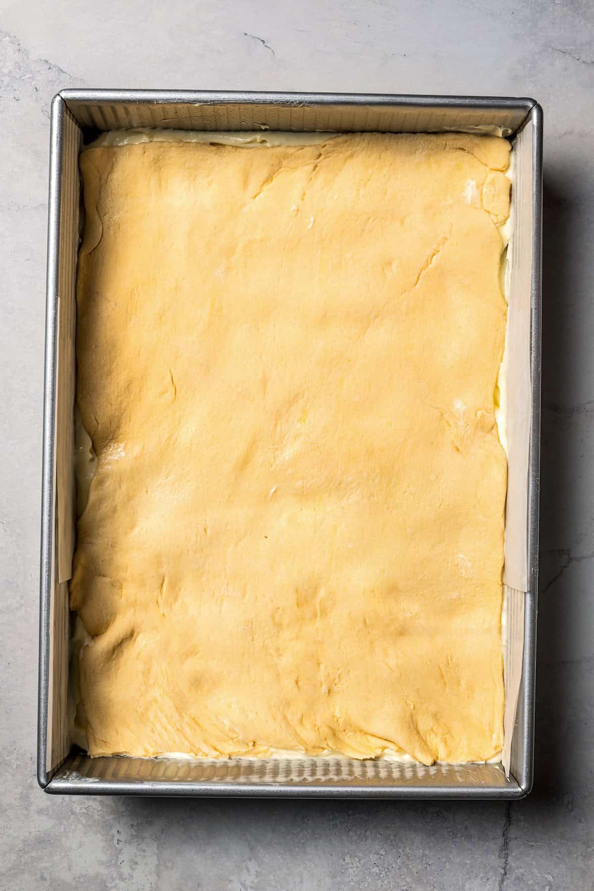 This churro cheesecake bars recipe is an easy dessert with layers of cinnamon sugar, a flaky pastry crust, and creamy cheesecake filling. Top crust added on top of the cheesecake layer in a baking pan.