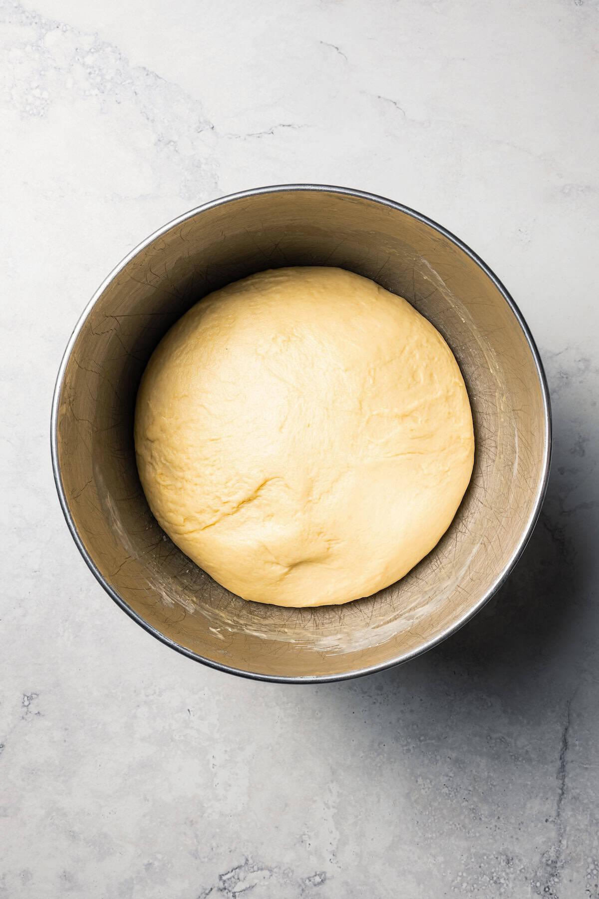 This cinnamon roll recipe makes big, bakery-style cinnamon buns filled with gooey cinnamon sugar and topped with sweet cream cheese frosting. A ball of cinnamon roll dough in a mixing bowl after the first rise.