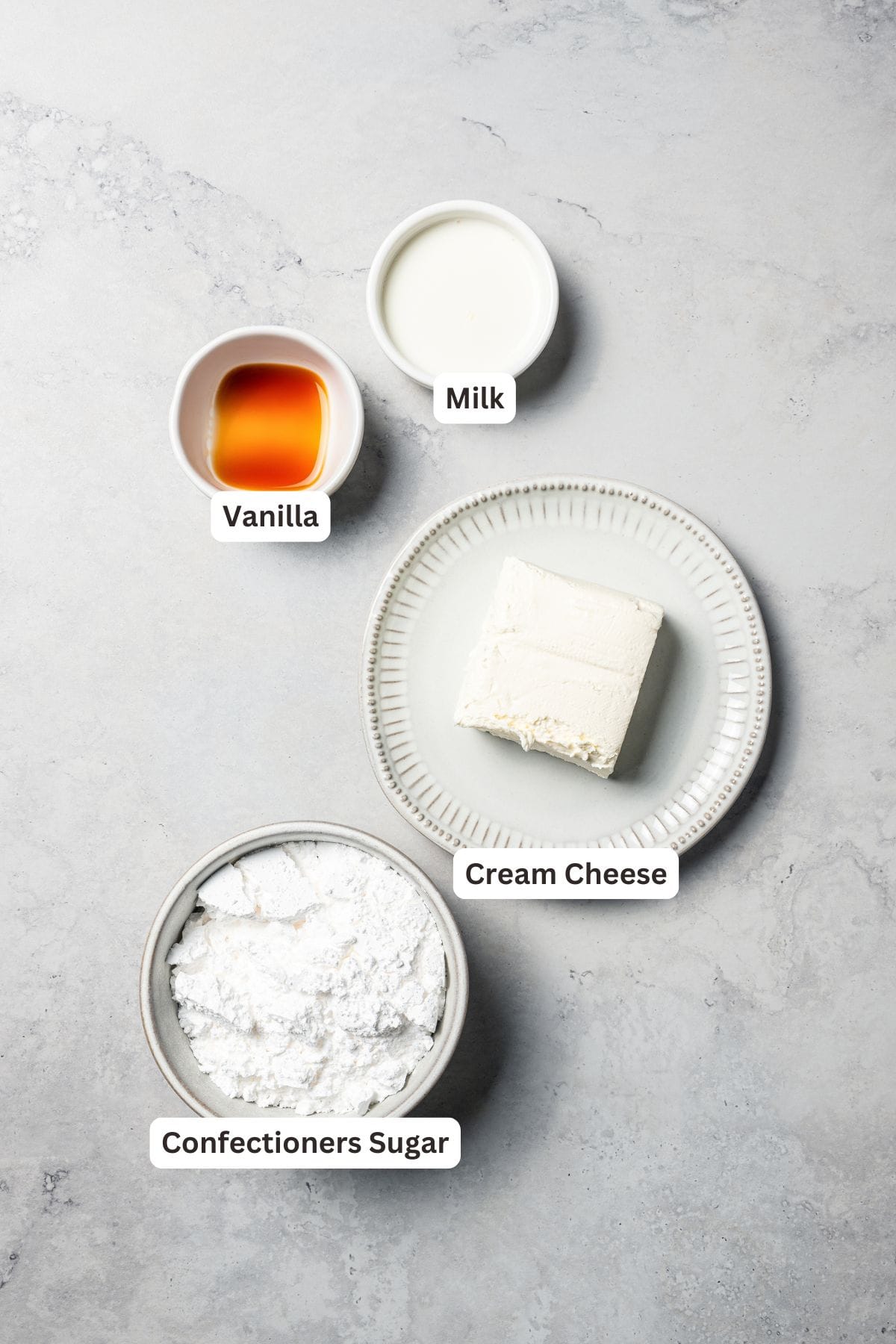 This cinnamon roll recipe makes big, bakery-style cinnamon buns filled with gooey cinnamon sugar and topped with sweet cream cheese frosting. Cinnamon roll frosting ingredients with text labels overlaying each ingredient.