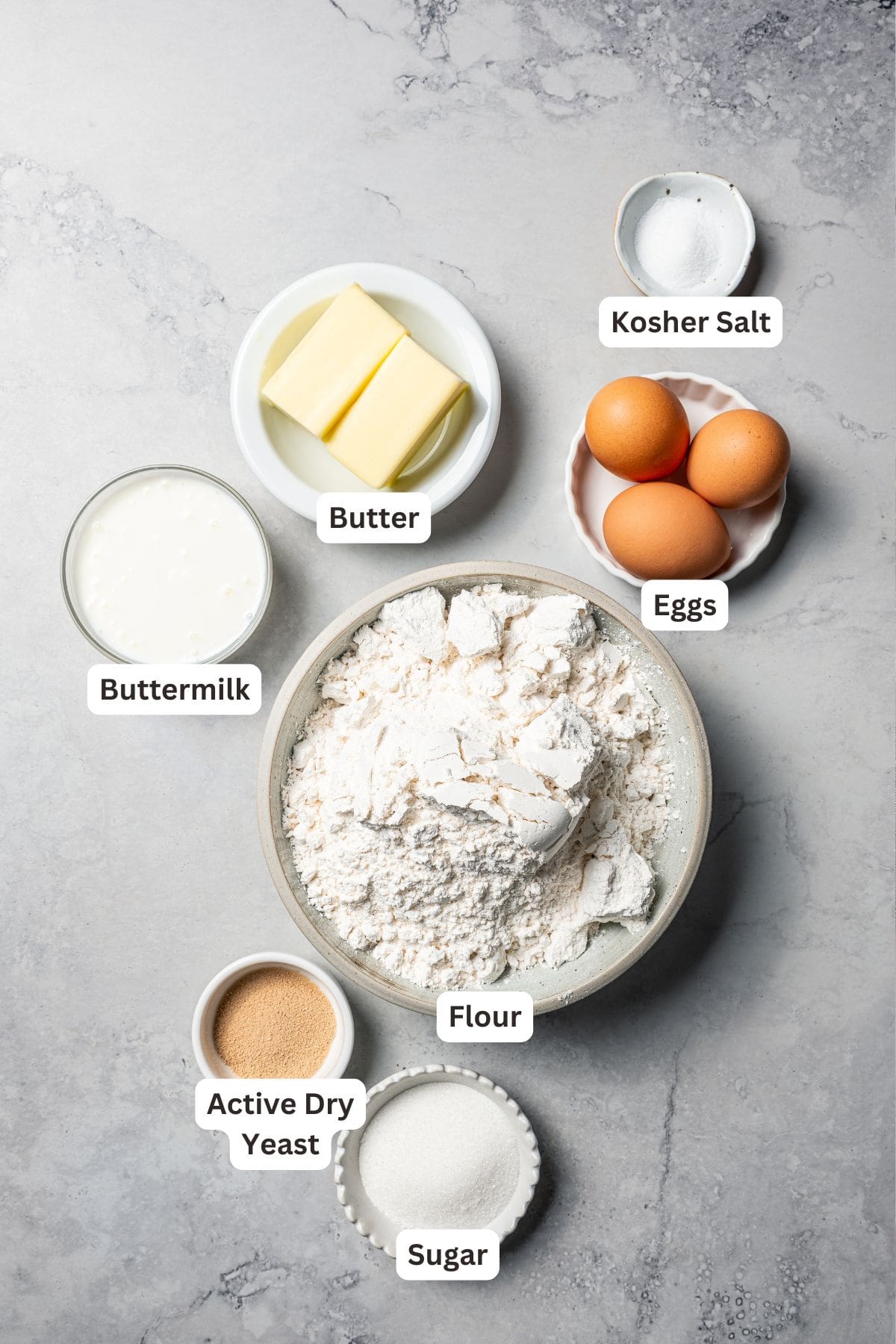 This cinnamon roll recipe makes big, bakery-style cinnamon buns filled with gooey cinnamon sugar and topped with sweet cream cheese frosting. Cinnamon roll dough ingredients with text labels overlaying each ingredient.