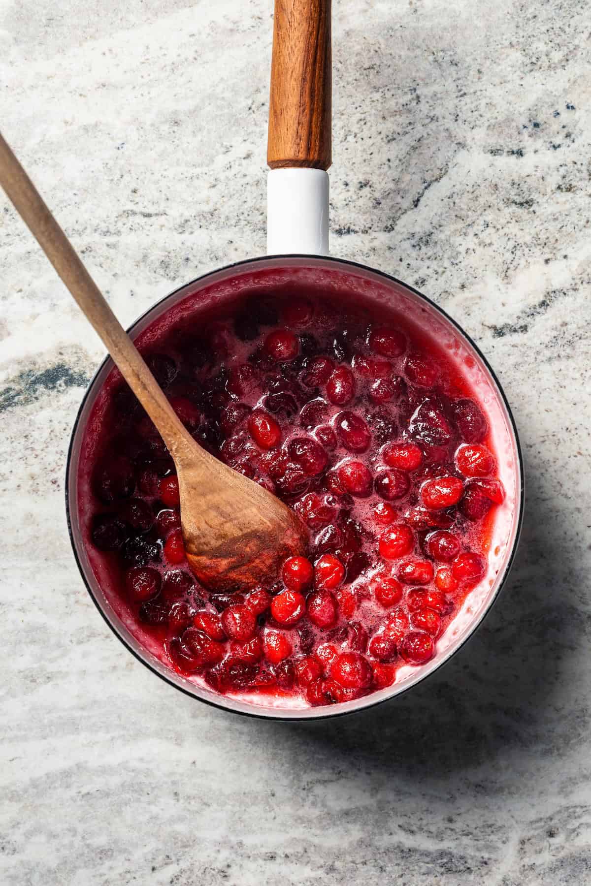 Pumpkin pancakes are the best fall breakfast! Made from pancake mix, real pumpkin, and spices, topped with cranberry syrup for the holidays. Fresh cranberries simmering in a saucepan.