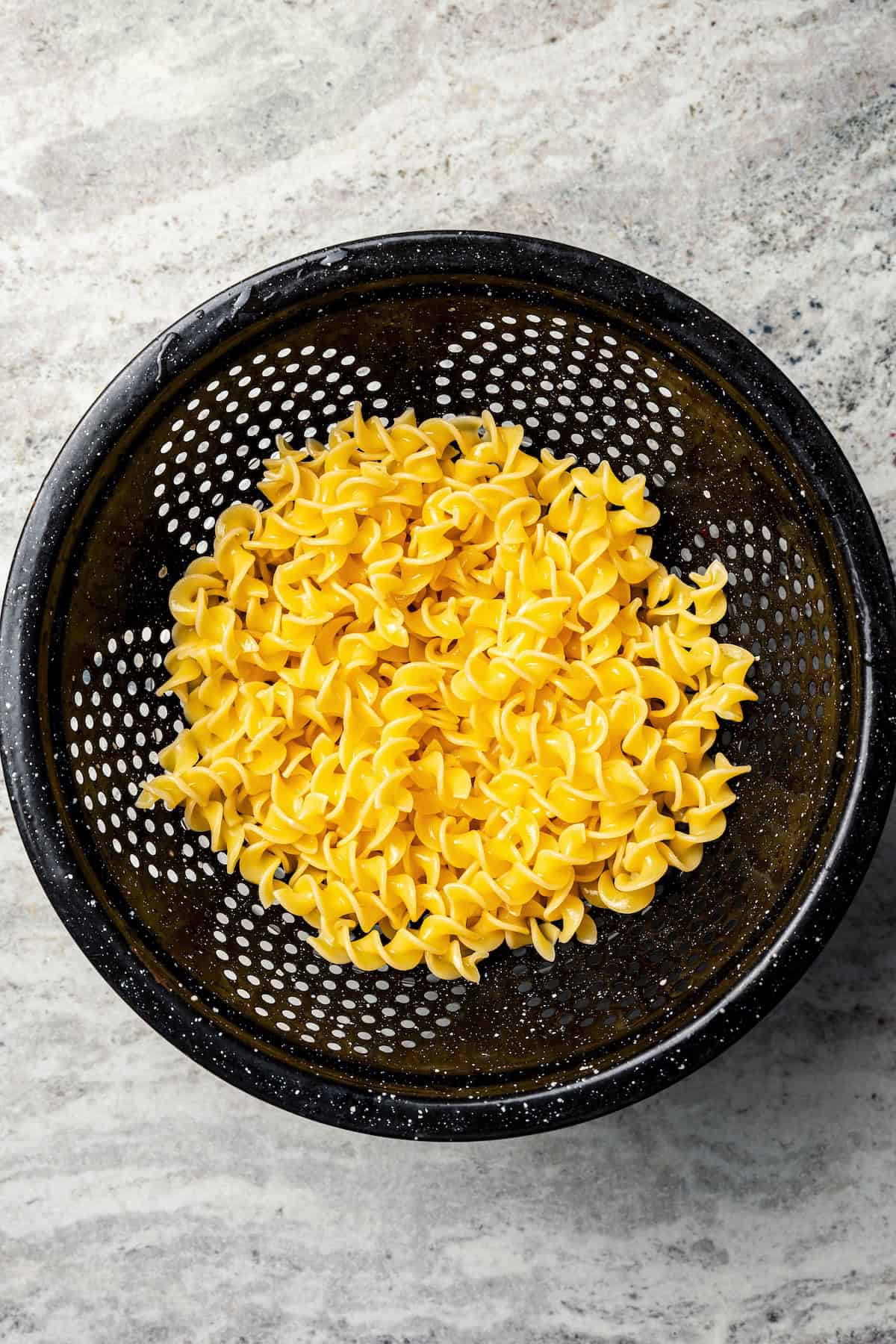 Drained egg noodles in a colander.