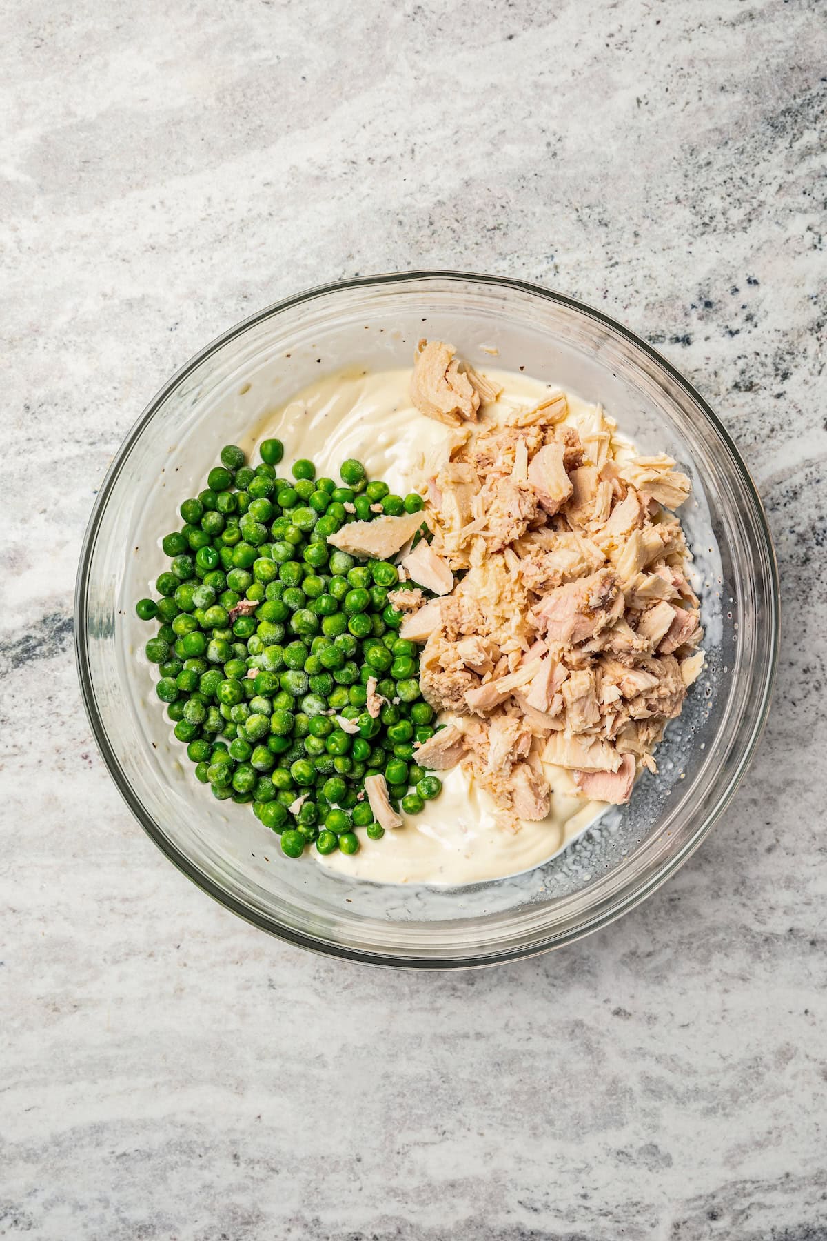 Tuna and frozen peas added to a bowl with cream of chicken soup.